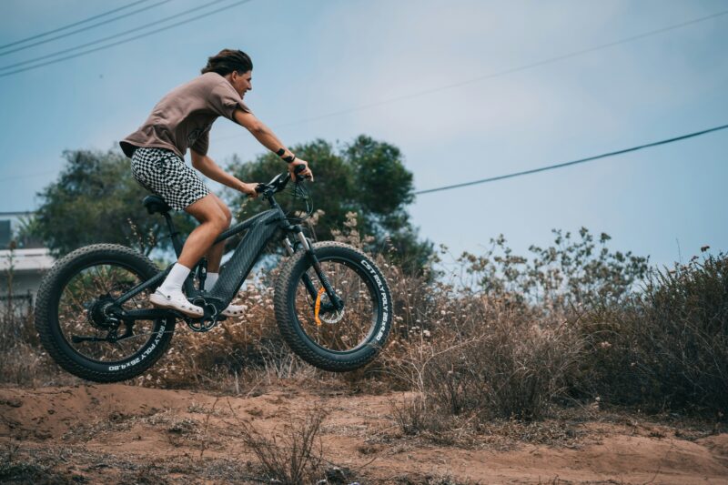 ファットタイヤの電動マウンテンバイクで未舗装路を走る男性