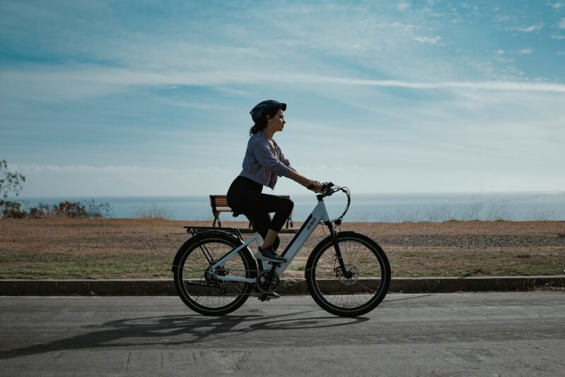 海沿いの道路を白い低床フレームの電動アシスト自転車で走る女性