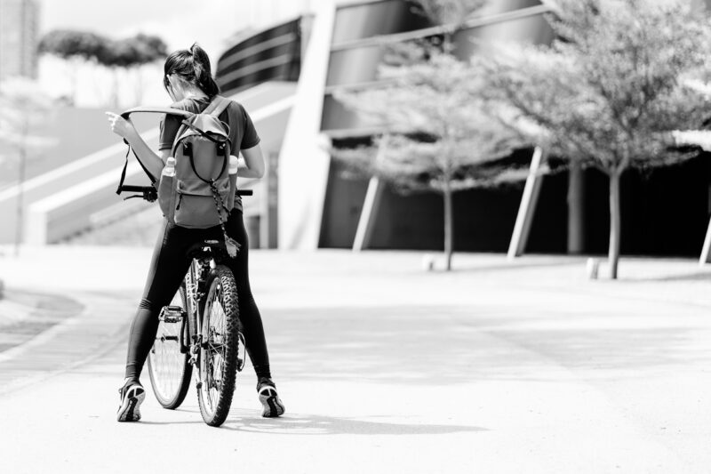 リュックを背負った女性がスポーツタイプの自転車にまたがっている様子