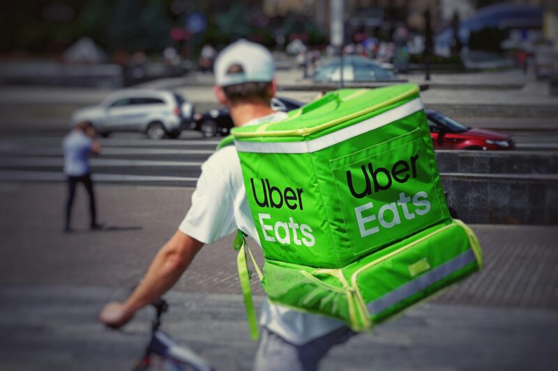 Uber Eatsの大型配達バッグを背負って自転車で配達する配達員