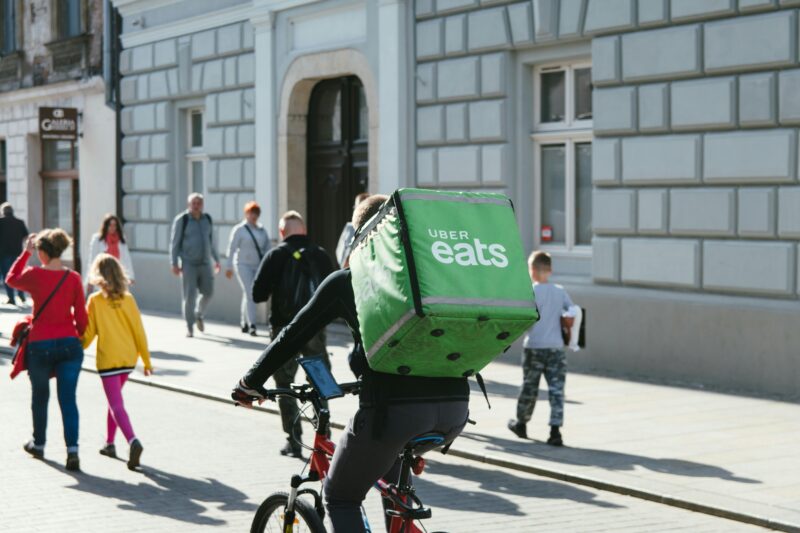 Uber Eatsの配達バッグを背負って街中を自転車で走る配達員
